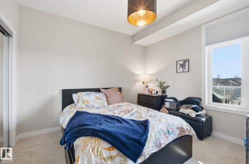 Bedroom with baseboards and light colored carpet - 309 625 Leger Way, Edmonton, AB - Indoor Photo Showing Bedroom