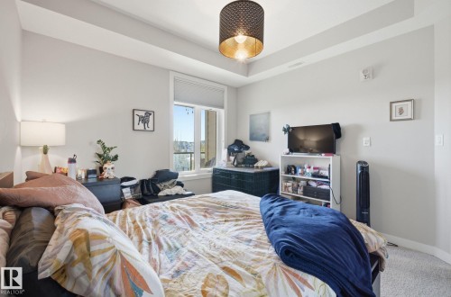 Bedroom featuring carpet flooring and a tray ceiling - 309 625 Leger Way, Edmonton, AB - Indoor Photo Showing Bedroom