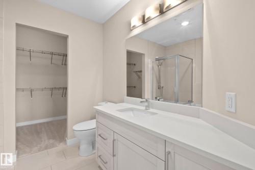 Bathroom featuring a single vanity with stone-finish countertop, undermount sink, and chrome faucet - 309 625 Leger Way, Edmonton, AB - Indoor Photo Showing Bathroom