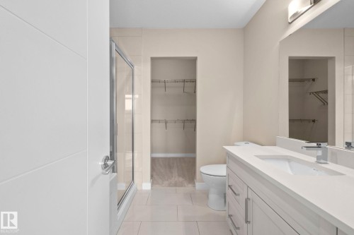 Modern bathroom featuring a single vanity with a solid surface countertop, an integrated rectangular sink, and a chrome faucet - 309 625 Leger Way, Edmonton, AB - Indoor Photo Showing Bathroom