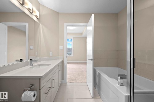 Contemporary bathroom featuring a long vanity with a single integrated sink, light-toned countertop, and chrome faucet - 309 625 Leger Way, Edmonton, AB - Indoor Photo Showing Bathroom