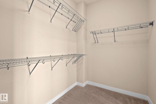 Walk-in closet featuring wire shelving, wire hanging rods, neutral wall paint, white trim, and carpet flooring - 309 625 Leger Way, Edmonton, AB - Indoor With Storage