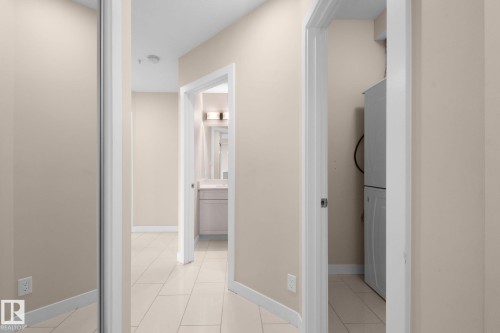 Hallway featuring light-toned walls, tile flooring, and white baseboards - 309 625 Leger Way, Edmonton, AB - Indoor