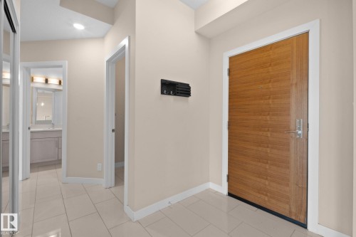 Wood-finish entry door with contemporary hardware - 309 625 Leger Way, Edmonton, AB - Indoor Photo Showing Other Room