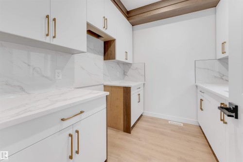 Kitchen featuring light wood-style floors, light stone counters, tasteful backsplash, and dual tone cabinets - 13 Trill Point(E), Spruce Grove, AB - Indoor Photo Showing Kitchen