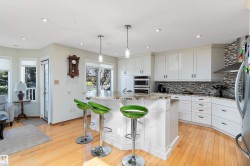 Spacious kitchen with a bar, granite counters, pendant lighting, a center island, and stainless steel appliances - 