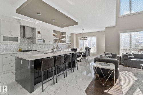 Kitchen with modern cabinets, an island with sink, decorative light fixtures, a kitchen bar, and dual tone cabinets - 1611 158 Street, Edmonton, AB - Indoor Photo Showing Kitchen With Upgraded Kitchen