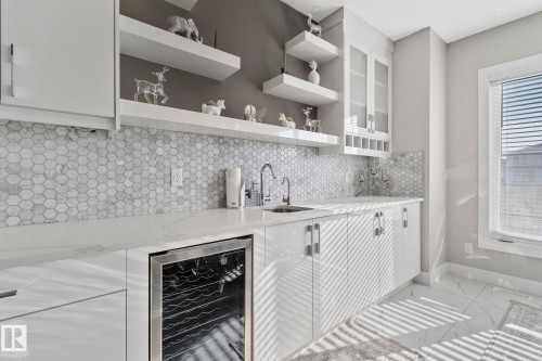 Kitchen with beverage cooler, light stone counters, light marble finish floors, and tasteful backsplash - 1611 158 Street, Edmonton, AB - Indoor Photo Showing Kitchen