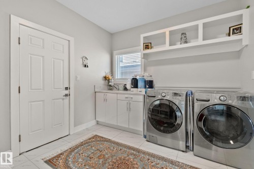 Laundry area with light marble finish floors, separate washer and dryer, and cabinet space - 1611 158 Street, Edmonton, AB - Indoor Photo Showing Laundry Room