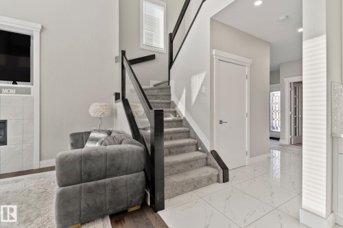 Staircase with a tiled fireplace and marble finish flooring - 1611 158 Street, Edmonton, AB - Indoor Photo Showing Other Room With Fireplace
