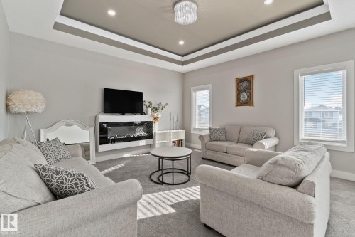 Carpeted living room featuring recessed lighting, a raised ceiling, and a glass covered fireplace - 1611 158 Street, Edmonton, AB - Indoor Photo Showing Living Room With Fireplace
