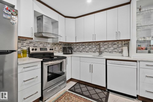 Kitchen featuring stainless steel appliances, white cabinets, and decorative backsplash - 1611 158 Street, Edmonton, AB - Indoor Photo Showing Kitchen With Upgraded Kitchen