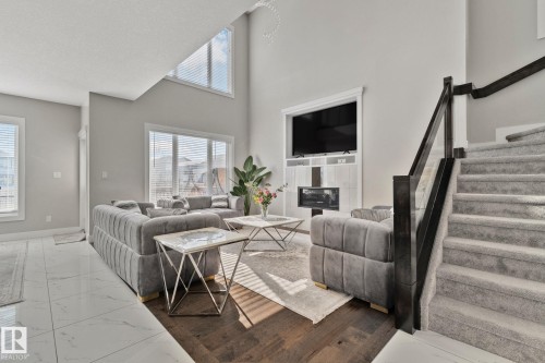 Living area featuring marble look tile flooring, a high ceiling, and a glass covered fireplace - 1611 158 Street, Edmonton, AB - Indoor With Fireplace