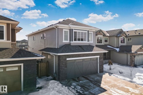 View of front of house with a shingled roof, a garage, a residential view, and stone siding - 1611 158 Street, Edmonton, AB - Outdoor