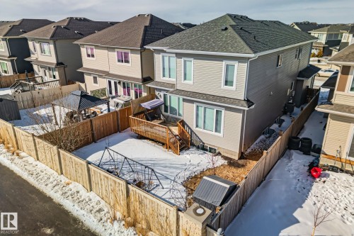 Snow covered house featuring a residential view, a fenced backyard, a wooden deck, and roof with shingles - 1611 158 Street, Edmonton, AB - Outdoor With Exterior