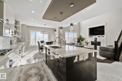 Kitchen featuring hanging light fixtures, modern cabinets, stainless steel appliances, plenty of natural light, and a raised ceiling - 1611 158 Street, Edmonton, AB - Indoor Photo Showing Kitchen With Upgraded Kitchen