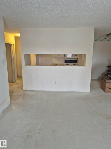 Unfurnished living room with concrete flooring and a textured ceiling - 410 17467 98A Avenue, Edmonton, AB - Indoor