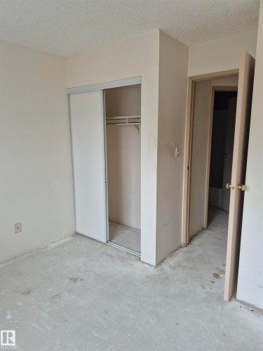 Unfurnished bedroom with a textured ceiling, a closet, and unfinished concrete floors - 410 17467 98A Avenue, Edmonton, AB - Indoor Photo Showing Other Room