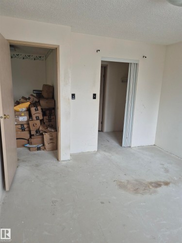 Unfurnished room featuring a textured ceiling and unfinished concrete flooring - 410 17467 98A Avenue, Edmonton, AB - Indoor Photo Showing Other Room