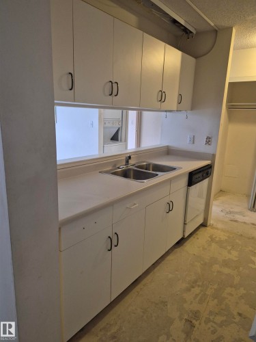 Kitchen featuring light countertops, dishwasher, a textured ceiling, and white cabinetry - 410 17467 98A Avenue, Edmonton, AB - Indoor Photo Showing Kitchen With Double Sink