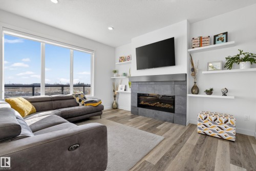 Living room featuring a tiled fireplace, light wood finished floors, and recessed lighting - 9727 205 Street, Edmonton, AB - Indoor Photo Showing Living Room With Fireplace