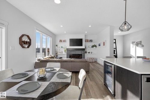 Dining space with beverage cooler, a tiled fireplace, light wood finished floors, and recessed lighting - 9727 205 Street, Edmonton, AB - Indoor Photo Showing Dining Room