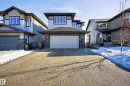 View of front facade featuring stone siding, driveway, an attached garage, and board and batten siding - 9727 205 Street, Edmonton, AB  - Outdoor With Facade 