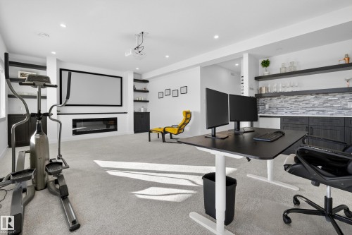 Workout room featuring light colored carpet, a dry bar, a glass covered fireplace, and recessed lighting - 9727 205 Street, Edmonton, AB - Indoor Photo Showing Gym Room