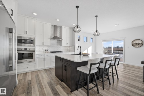 Two tone kitchen with two tone color scheme, stainless steel appliances, a kitchen bar, a center island with sink, and pendant lighting - 9727 205 Street, Edmonton, AB - Indoor Photo Showing Kitchen With Upgraded Kitchen