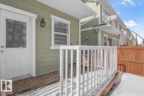 The property features an exterior with green siding, a deck with white railings, and a wooden fence - 6 6410 134 Avenue Nw, Edmonton, AB - Outdoor With Deck Patio Veranda With Exterior