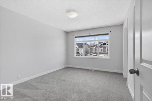 This room features light grey carpeting, white baseboards, and a window with white trim - 6 6410 134 Avenue Nw, Edmonton, AB - Indoor