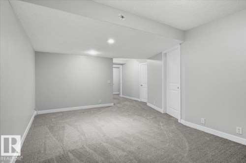 Spacious room featuring light gray walls, plush gray carpeting, and recessed lighting - 6 6410 134 Avenue Nw, Edmonton, AB - Indoor