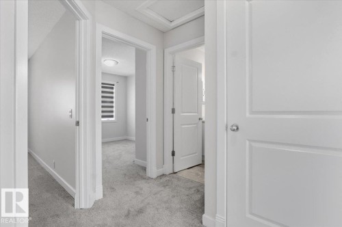 The property features light gray carpeting throughout the hallway and into a room with a window, providing natural light - 6 6410 134 Avenue Nw, Edmonton, AB - Indoor Photo Showing Other Room
