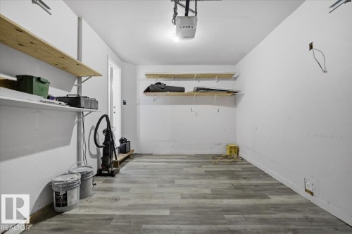 This spacious garage features light gray walls, shelving for storage, and gray flooring - 6 6410 134 Avenue Nw, Edmonton, AB - Indoor Photo Showing Garage