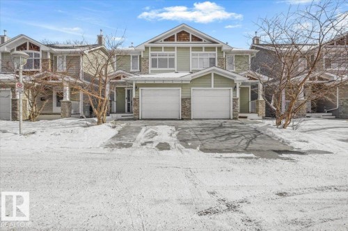 The property features a two-car garage, a light green exterior, and stone accents - 6 6410 134 Avenue Nw, Edmonton, AB - Outdoor With Facade