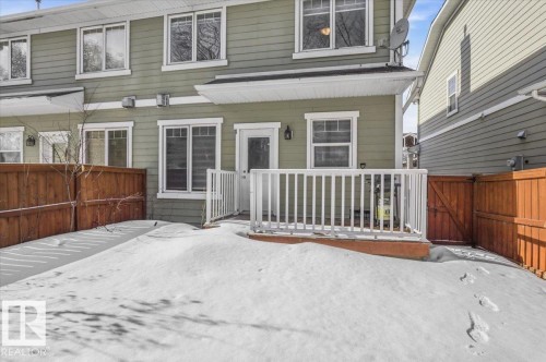 The property features a private deck with white railings, a fenced yard, and light green siding - 6 6410 134 Avenue Nw, Edmonton, AB - Outdoor