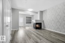 The living area features durable flooring, a modern fireplace, and a decorative accent wall - 6 6410 134 Avenue Nw, Edmonton, AB  - Indoor With Fireplace 