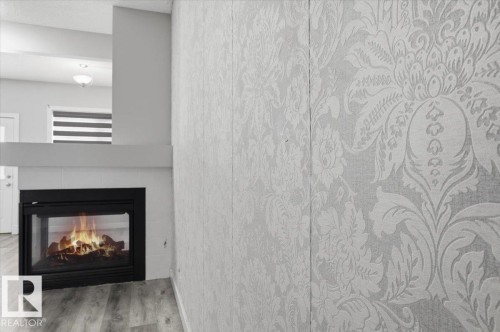 The property features a modern fireplace with a black frame, set against a white mantel - 6 6410 134 Avenue Nw, Edmonton, AB - Indoor Photo Showing Living Room With Fireplace