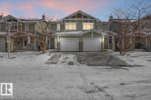 The property features a two-car garage, stone accents on the facade, and multiple windows - 6 6410 134 Avenue Nw, Edmonton, AB - Outdoor With Facade