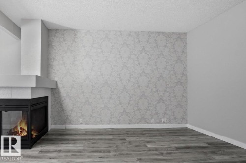 This property features a corner fireplace with a contemporary design and a visible flame - 6 6410 134 Avenue Nw, Edmonton, AB - Indoor With Fireplace