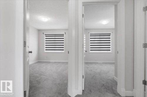 The property features rooms with grey carpeting and windows fitted with striped blinds - 6 6410 134 Avenue Nw, Edmonton, AB - Indoor Photo Showing Other Room