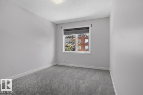 This room features light grey walls, grey carpeting, white baseboards, and a window with a dark roller blind - 6 6410 134 Avenue Nw, Edmonton, AB - Indoor Photo Showing Other Room