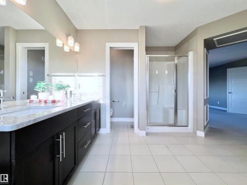 Full bathroom featuring a stall shower, double vanity, a textured ceiling, and light tile patterned floors - 4604 Westcliff Point(E), Edmonton, AB - Indoor Photo Showing Bathroom