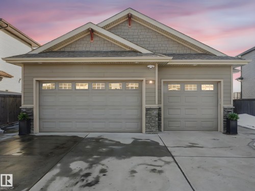 View of front of house with stone siding, concrete driveway, and a shingled roof - 117 Mcdowell Wynd, Leduc, AB - Outdoor
