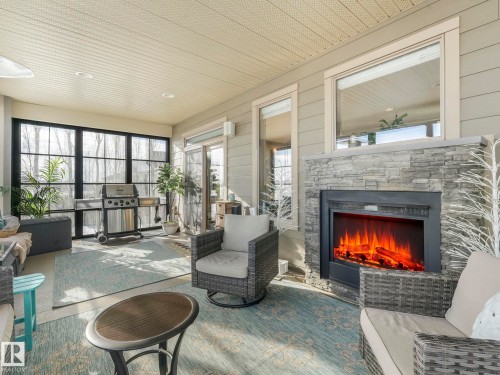 Sunroom with plenty of natural light and an outdoor living space with a fireplace - 117 Mcdowell Wynd, Leduc, AB - Indoor Photo Showing Living Room With Fireplace