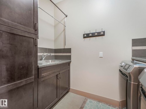 Laundry area featuring separate washer and dryer, cabinet space, and light tile patterned floors - 117 Mcdowell Wynd, Leduc, AB - Indoor Photo Showing Laundry Room
