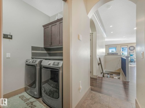 Laundry room featuring arched walkways, cabinet space, separate washer and dryer, light tile patterned flooring, and recessed lighting - 117 Mcdowell Wynd, Leduc, AB - Indoor Photo Showing Laundry Room
