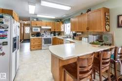 Kitchen with white appliances, decorative backsplash, a peninsula, a kitchen bar, and light countertops - 