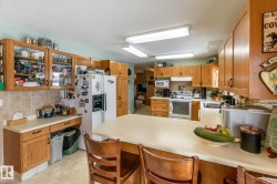 Kitchen with a peninsula, white appliances, light countertops, a breakfast bar, and glass fronted cabinets - 