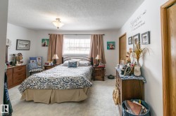Bedroom featuring a textured ceiling and light colored carpet - 